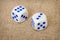 Two playing dices with blue points on brown canvas