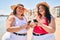 Two plus size overweight sisters twins women happy at the beach on summer holidays with smartphone
