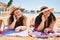 Two plus size overweight sisters twins women lying at beach speaking on the phone on summer holidays