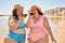 Two plus size overweight sisters twins women sending a voice message on smartphone the beach on summer holidays