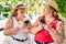 Two plus size overweight sisters twins women with smartphone outdoors on a sunny day