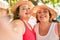 Two plus size overweight sisters twins women smiling taking a selfie picture with the phone outdoors