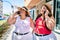 Two plus size overweight sisters twins women speaking on the phone outdoors on a sunny day