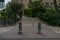 Two poles symmetrical outside street bridge with green nature bushes around it. People in the background beautiful small walk