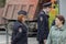 Two policemen, a man and a woman. A woman looks closely at people passing by.