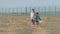 Two poor children refugees family girl and boy with toy walking along desert with razor barbed fence on state border