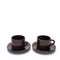 Two porcelain coffee cups and saucers stand side by side.