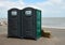 Two Portaloo cubicles on seafront promenade with the ocean in the background.