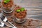 Two portions Classic tiramisu dessert in a glass on wooden background