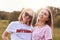 Two positive female friends wear t shirt and shades, spend free time on nature, smile pleasantly at camera, have good relationship