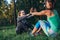 Two positive girlfriends doing partner sit-up exercise with high-five in summer park