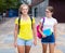Two positive girlfriends walking down street to college