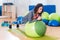 Two positive women doing plank exercise lying on balance ball in gym