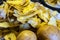 Two potatoes in the foreground and potato peels for the compost