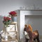 Two pots with poinsettia, Christmas star stand on a high stepped stool near the fireplace with figurines, by the Christmas tree