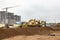 Two powerful excavators work at the same time on a construction site, sunny blue sky in the background. Construction equipment for