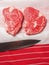 Two premium rib eye steaks on a white paper and red and white professional butcher apron and sharp blade of knife, Meat industry