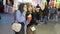 Two pretty adult girls eating street food at Valencia funfair attraction park with people on the background at night