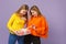 Two pretty blonde twins sisters girls in vivid clothes holding red striped present box with gift ribbon isolated on