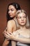 Two pretty diverse girls happy posing together: blond and brunette on brown background, lifestyle people concept