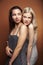 Two pretty diverse girls happy posing together: blond and brunette on brown background, lifestyle people concept