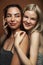 Two pretty diverse girls happy posing together: blond and brunette on brown background, lifestyle people concept