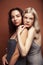 two pretty diverse girls happy posing together: blond and brunette on brown background, lifestyle people concept