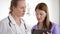 Two pretty female doctors discussing something on tablet at hospital room. Medical staff at work