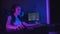 Two pretty gamer girls playing an online game in the dark neon gaming club