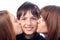 Two pretty girls kissing smiling boy