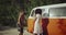 Two pretty girls making photo shoot on the road beside the vintage orange bus , happy dancing and smiling , wearing boho