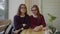 Two pretty girls students glasses sitting at the table in cafe looking at camera