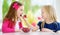 Two pretty little girls eating raspberries at home. Cute children enjoying their healthy fresh organic fruits and berries.
