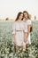 Two pretty sisters in a field of flowers. Spring beauty concept. Portrait shot of two gorgeous women. Beautiful joyful two girls