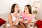 Two pretty sisters laughing in bedroom and drinking coffee