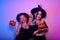 Two pretty witch poses with pumpkins for a Halloween photo. Girls in witch hats in neon dance at the party