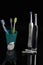 Two Professional Electric Toothbrushes In Front of Four Manual Tooth Brushes With Dental Floss and Extra Attachments On Black