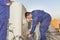 Two professional electricians are examining a heavy duty central air conditioning system on roof top