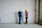 Two professional engineers in hardhats standing by wall and discussing sketch