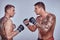 Two professional fighters looking at each other very close before the fight, isolated on a gray background.