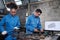 Two professional industry workers work with mechanical drawings on a monitor