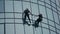 Two professional steeplejacks are working on the facade of the building