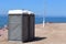 Two public restrooms in gray color on a beach.