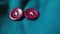two purple buttons on a teal cloth with a white button in the middle