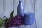 Two purple jars with cosmetic products and creams with fresh, blooming and fragrant lilac flowers