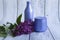 Two purple jars with cosmetic products and creams with fresh, blooming and fragrant lilac flowers