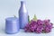 Two purple jars with cosmetic products and creams with fresh, blooming and fragrant lilac flowers