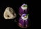 Two purple mousse desserts with white chocolate and pansy flower on black velvet background and a rock decoration