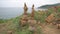 Two pyramids of stones stands on the sandy ground. Cairn on the hilltop above the sea