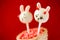 Two rabbit cake pops on red background.